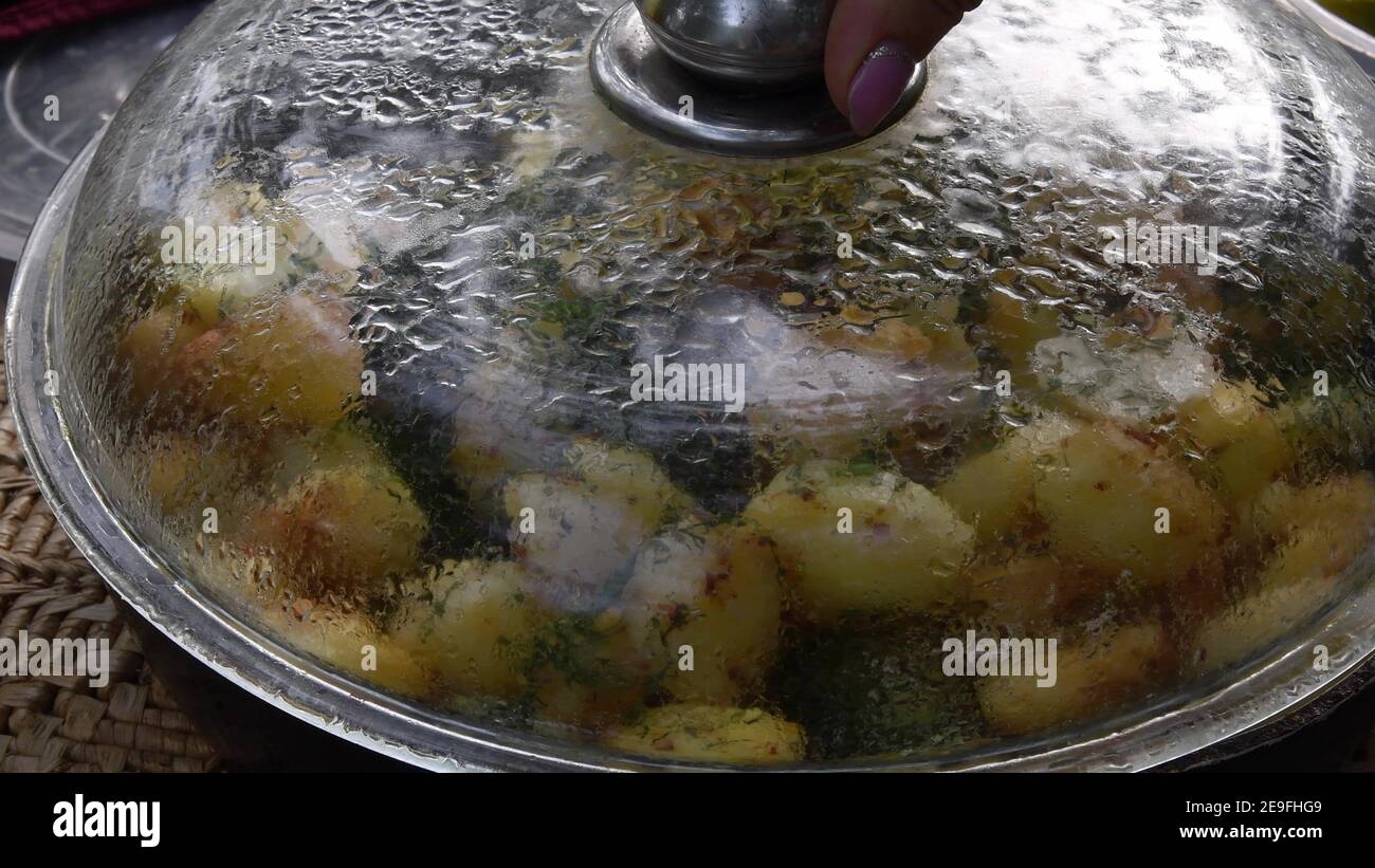 Wassertropfen Kondensation unter Glasdeckel der Pfanne voll von hausgemachten gerösteten Kartoffeln mit grünem Dill. Leckere lokale Küche der traditionellen Küche in Ost-E Stockfoto