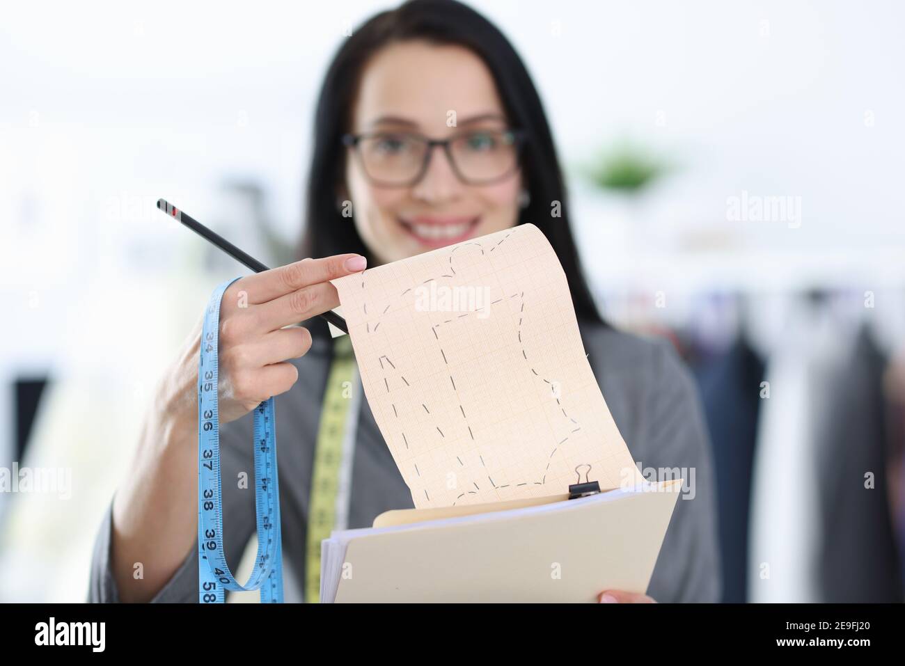 Frau Designerin hält Schimmel mit Skizzen von Kleidung Stockfoto