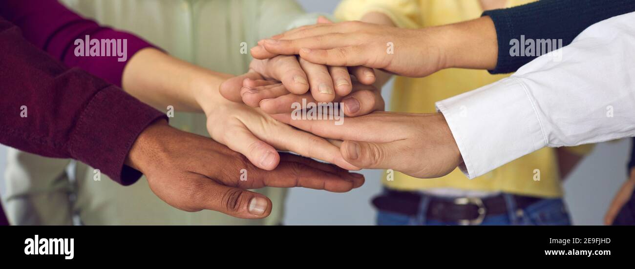 Nahaufnahme einer Gruppe von internationalen Menschen, die ihre Arme zusammenfalten und sich gegenseitig unterstützen. Stockfoto
