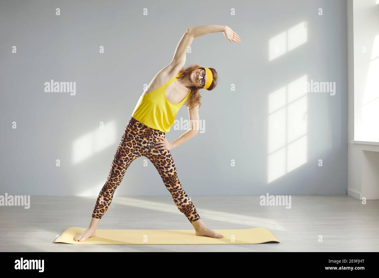 Happy Fitness-Geek tun stehende Seite biegen Übung während des Sports Trainieren Sie im sonnigen Fitnessstudio Stockfoto