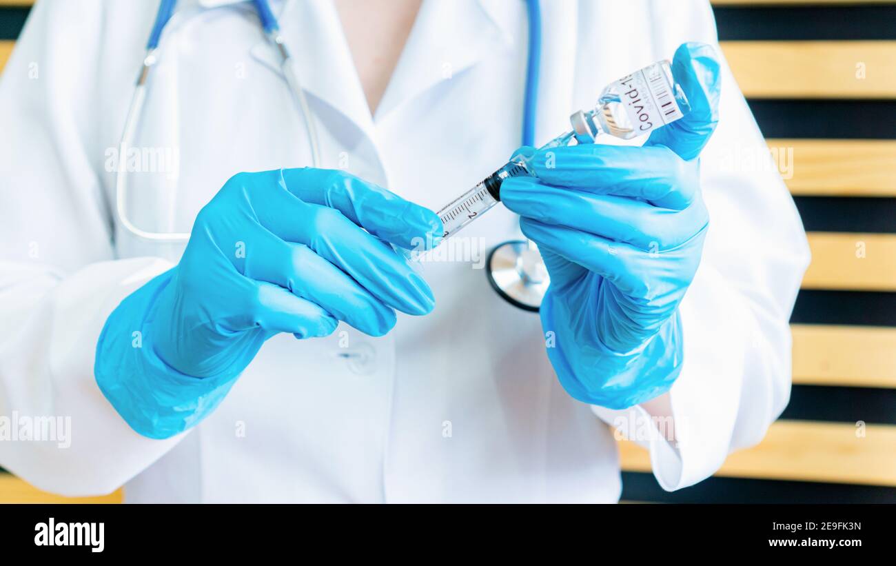 Der Arzt füllt eine Spritze mit dem Impfstoff COVID-19. Vorbereitung auf die Impfung. Testen eines Impfstoffs gegen eine Coronavirus-Infektion. Ein Arzt hält Stockfoto