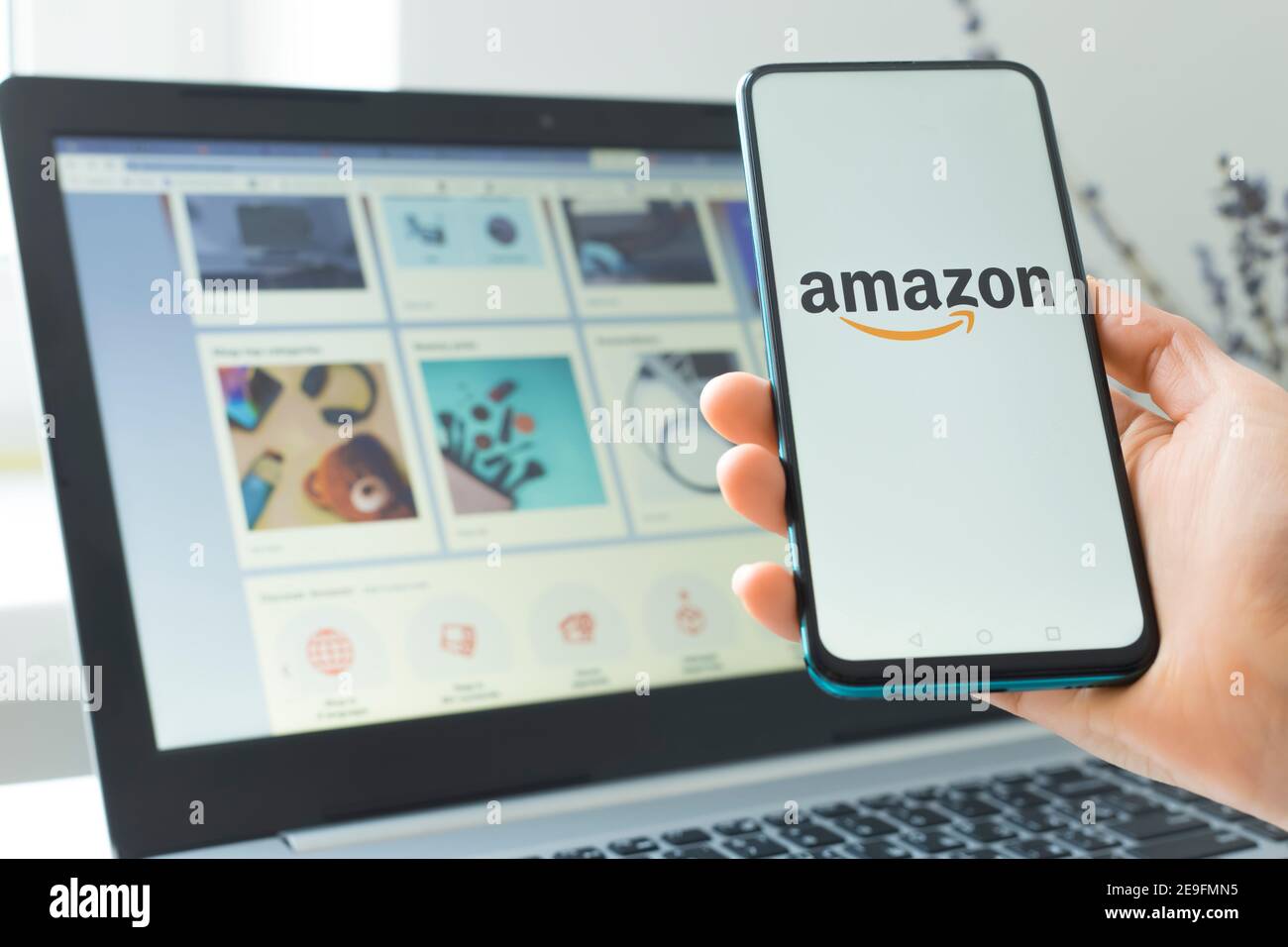 Kiew, Ukraine - 02. Februar 2021: Kauf von Waren im Amazon Online-Shop mit einem Smartphone und Laptop. Stockfoto