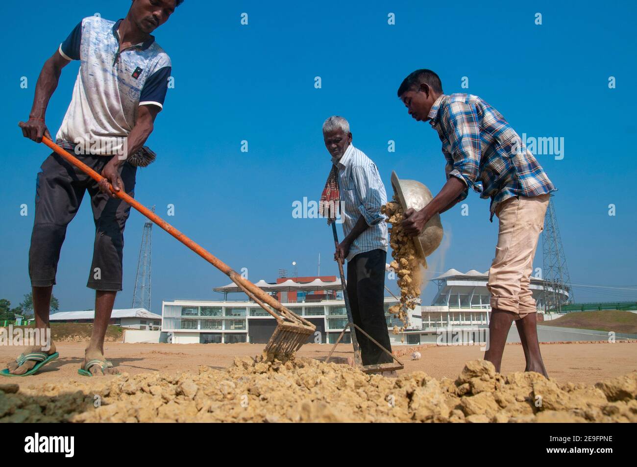Arbeiter bereiten den Boden mit dem Komplex und steht im Hintergrund im Bau. Das neue International Cricket Stadion im Teegarten Lakkatura von Sylhet hat sich bereits beim International Cricket Council (ICC) um internationale Anerkennung beworben. Bangladesch. Stockfoto