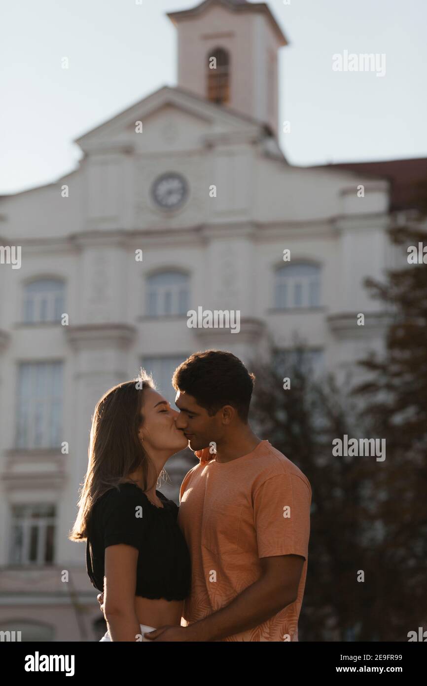 Junges Paar küsst sich vor dem verschwommenen Gebäude mit Copyspace. Verliebte Paare in der Stadt. Urbane Liebesgeschichte Stockfoto