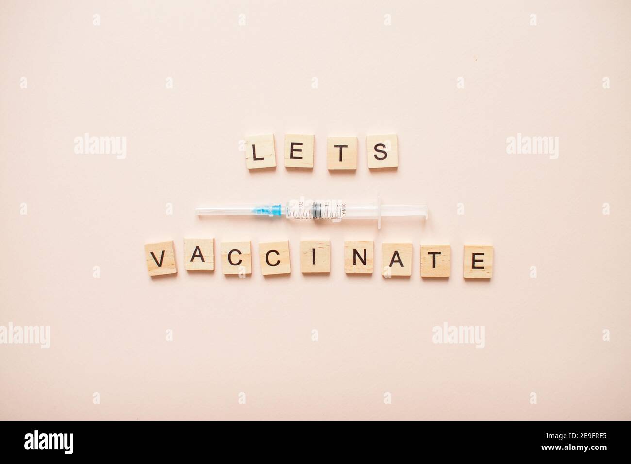 Phrase lässt impfen aus Holzblöcken auf einem Licht Rosa Hintergrund Stockfoto