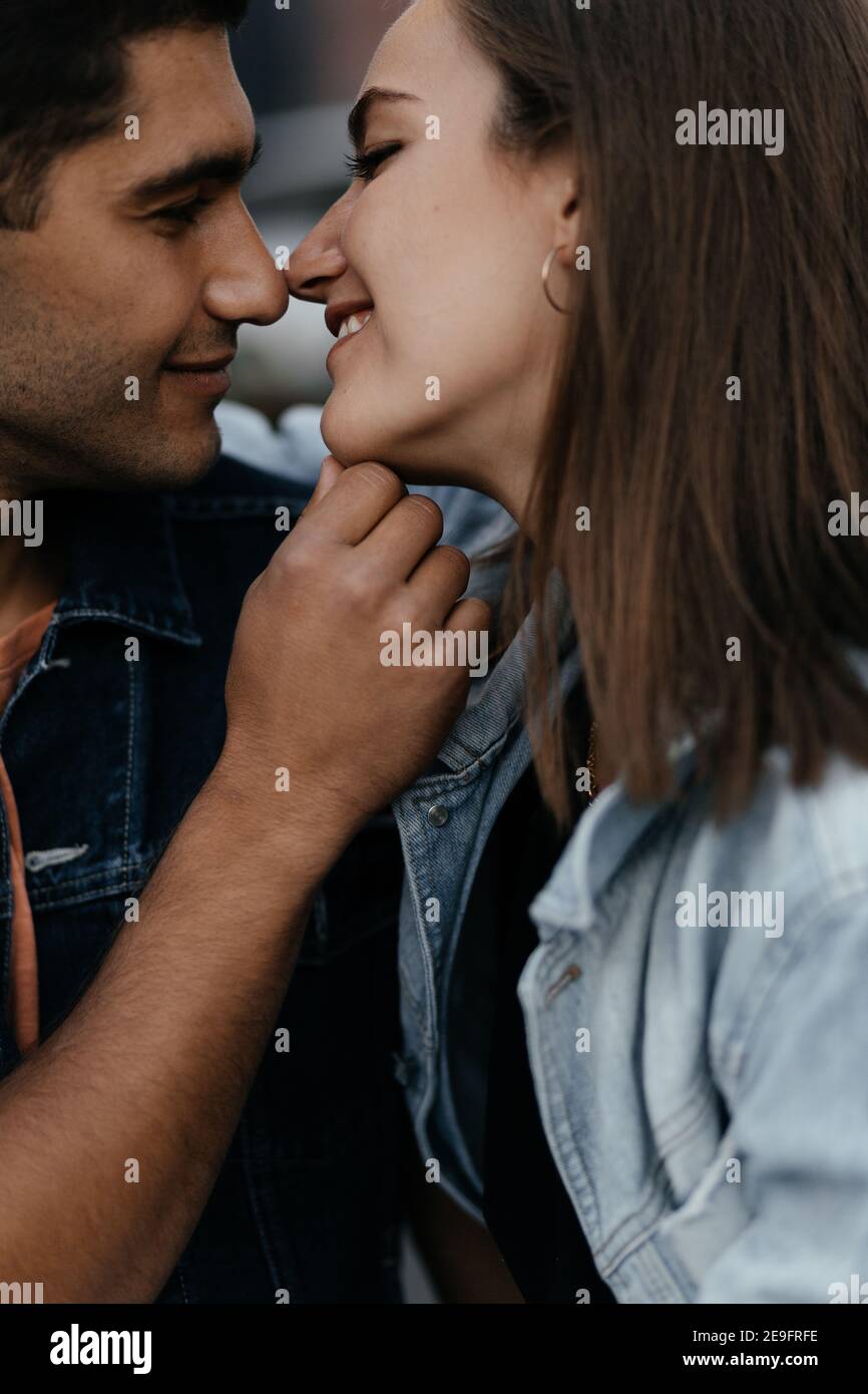 Glücklich junges Paar in der Liebe in lässigen Stil küssen mit ihren Nasen und lächeln gekleidet. Verliebte Paare in der Stadt. Urbane Liebesgeschichte Stockfoto