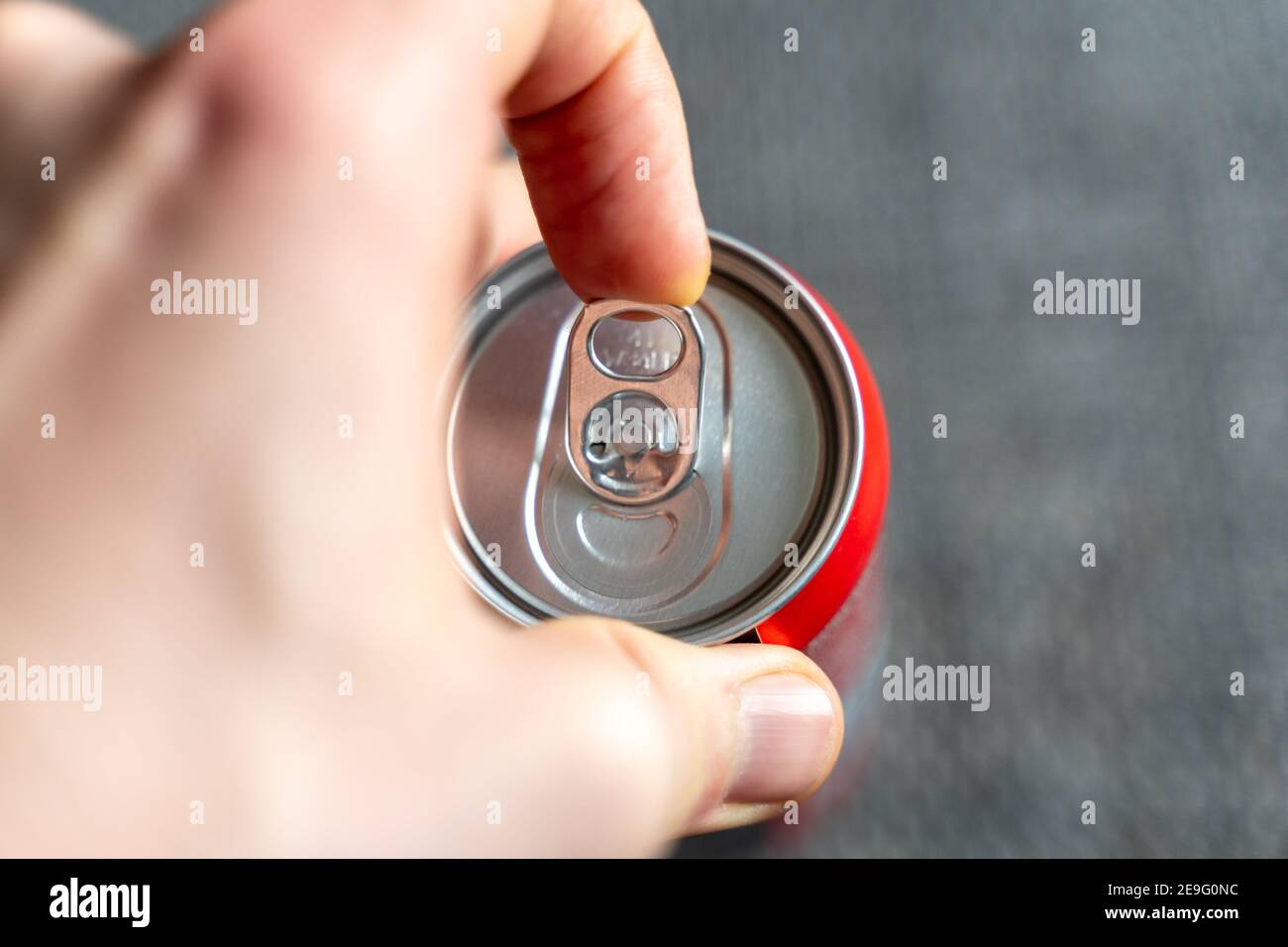 Ziehen der Lasche einer Getränkedose mit einer linken männlichen Hand. Nach einem anstrengenden Tag ein Erfrischungsgetränk wie Cola oder Energydrink öffnen Stockfoto