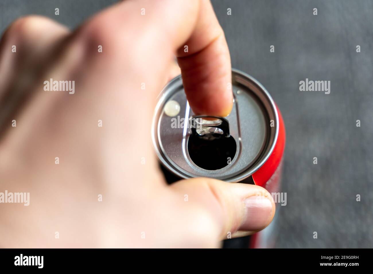 Ziehen der Lasche einer Getränkedose mit einer linken männlichen Hand. Nach einem anstrengenden Tag ein Erfrischungsgetränk wie Cola oder Energydrink öffnen Stockfoto