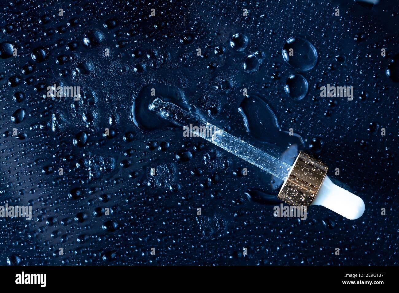 Feuchtigkeitsspendende Beauty-Produkte Konzept - klassisch blauer Hintergrund mit Medizin Pipette und Wasser spritzt um ihn herum Stockfoto