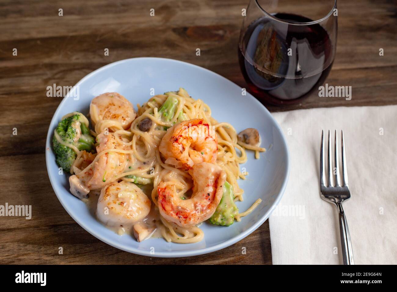 Linguiningingericht mit Garnelen und Jakobsmuscheln und einem Glas Rotwein Stockfoto