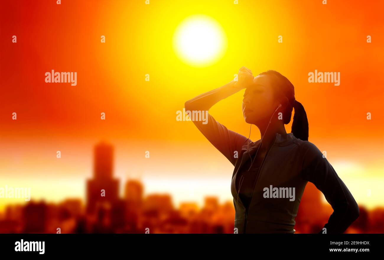 Frau, die ihre Augen vor der Sonne mit Sommerhitze schützt Im Hintergrund der Stadt Stockfoto