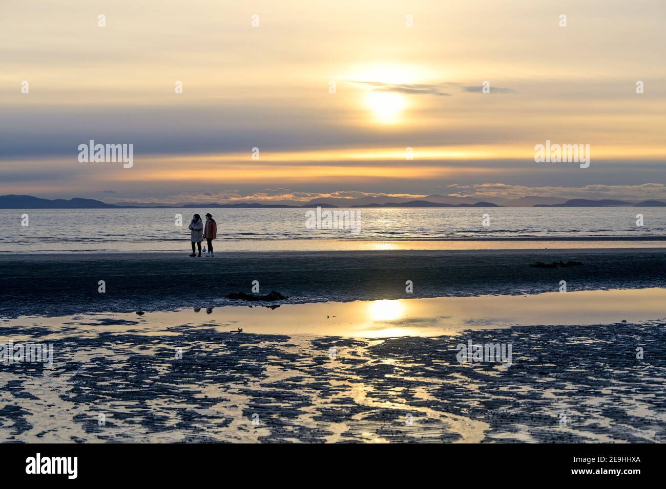 Junge Frauen am Strand, Sonnenuntergang, White Rock, British Columbia, Kanada Stockfoto