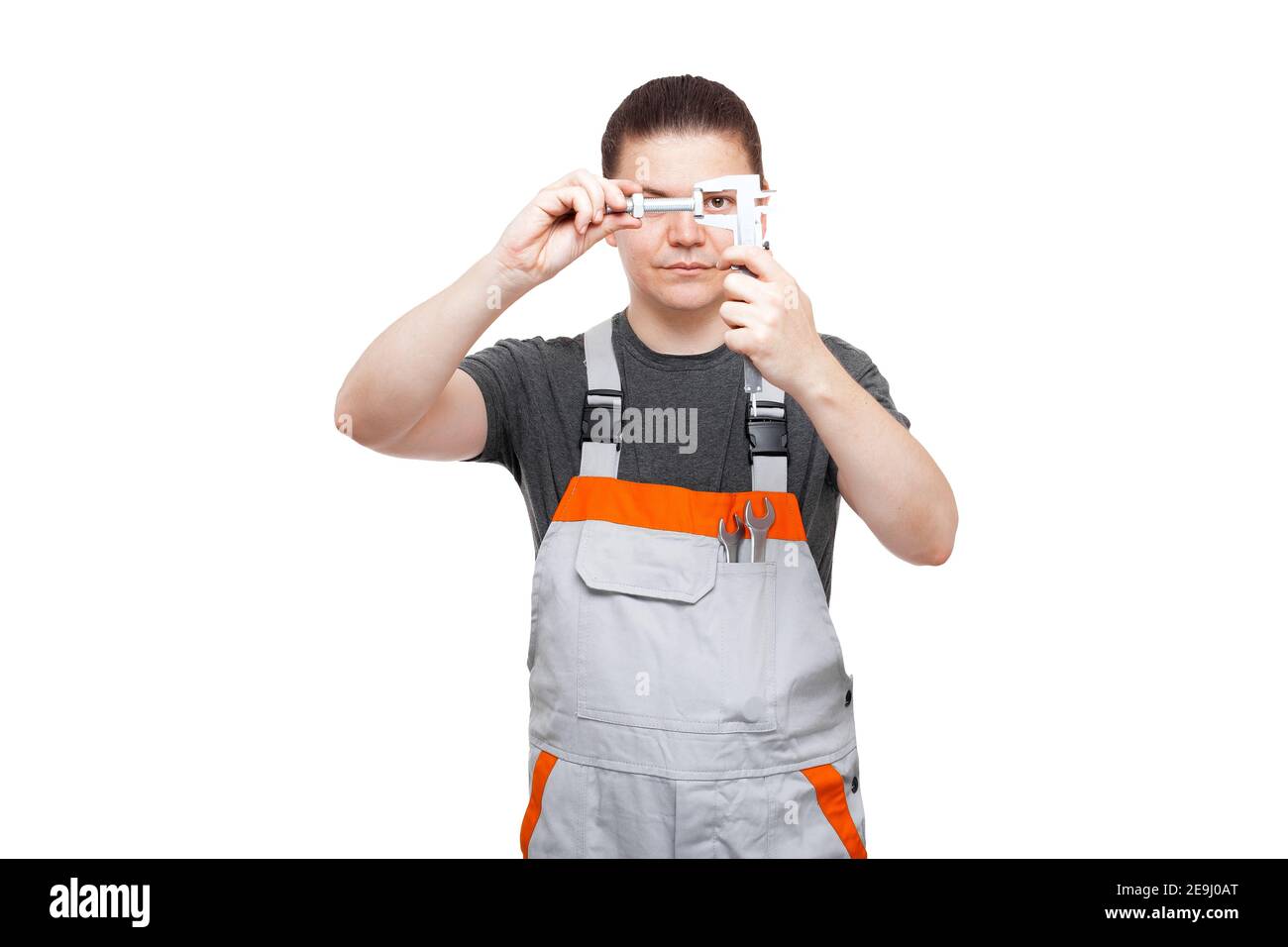 Männlicher Mechaniker in Uniform hält Bolzen und Messschieber ein Tasche mit Schraubenschlüssel nimmt Kontrolle Messung der Größe Aus Stahl Eisen Teil mit Th Stockfoto