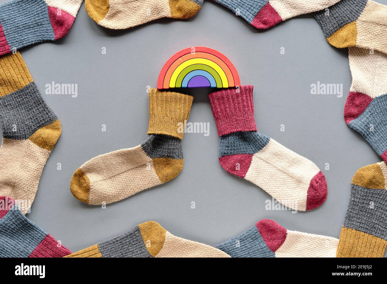 Tag Der Ungeraden Socken. Paar unpassende Schulsocken. Regenbogen aus Holz. Soziale Initiative gegen Mobbing in der Schule oder am Arbeitsplatz. Stockfoto