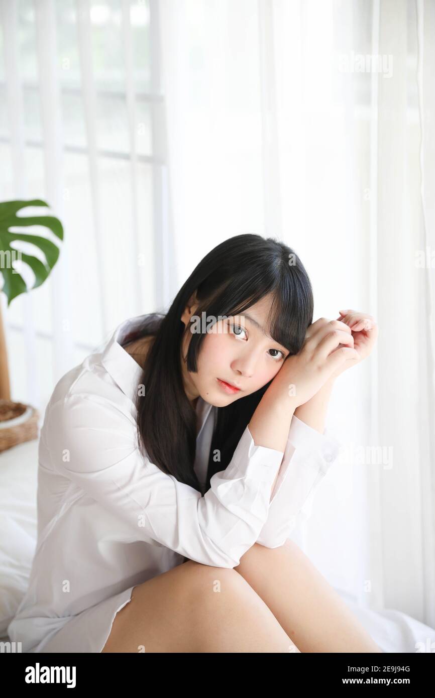 Portrait schöne asiatische Mädchen sitzen mit Uhr im weißen Schlafzimmer Stockfoto