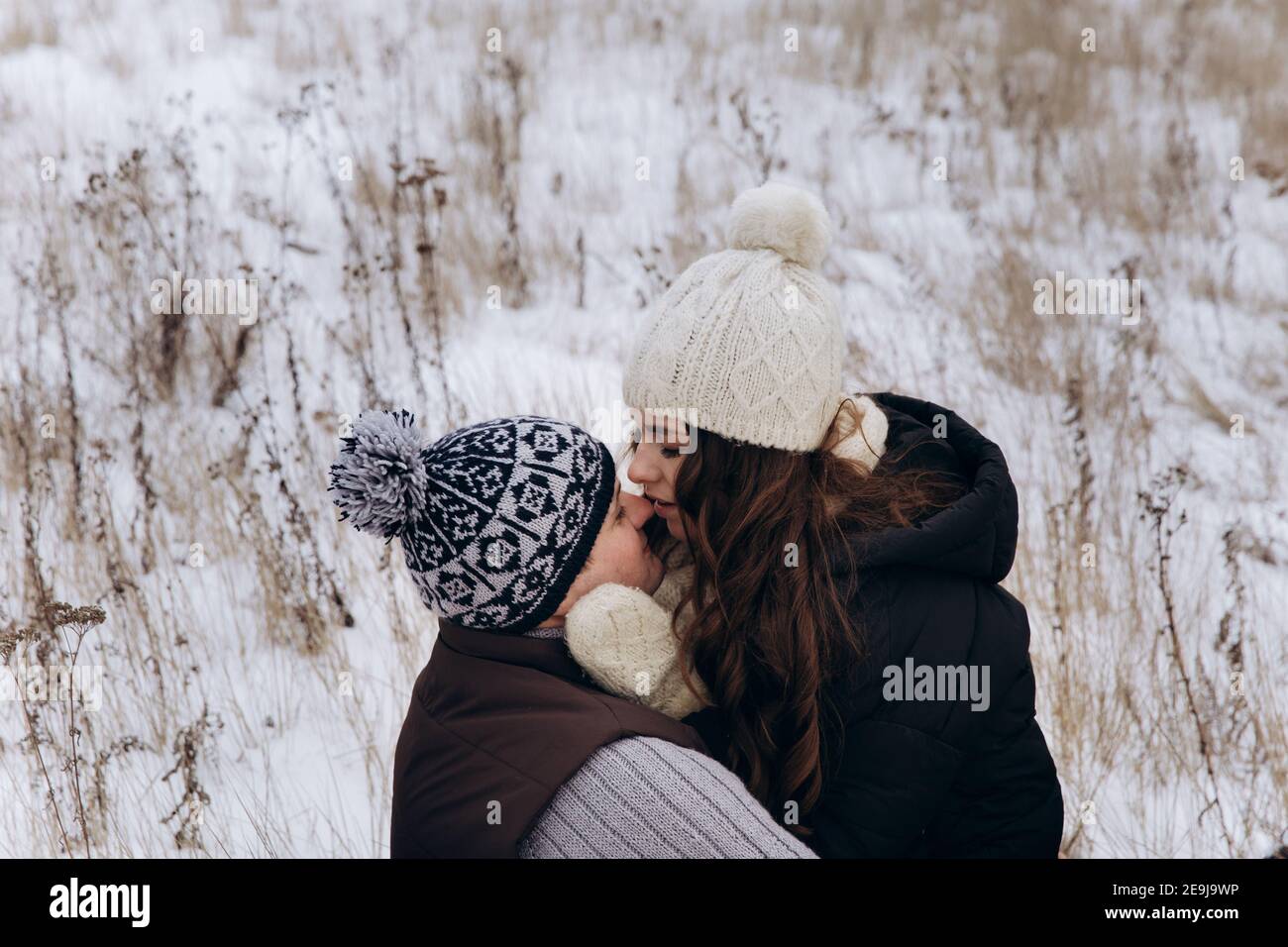 Eine Frau in einem weißen Hut küsst sehr sanft einen Mann auf die Nase. Stockfoto