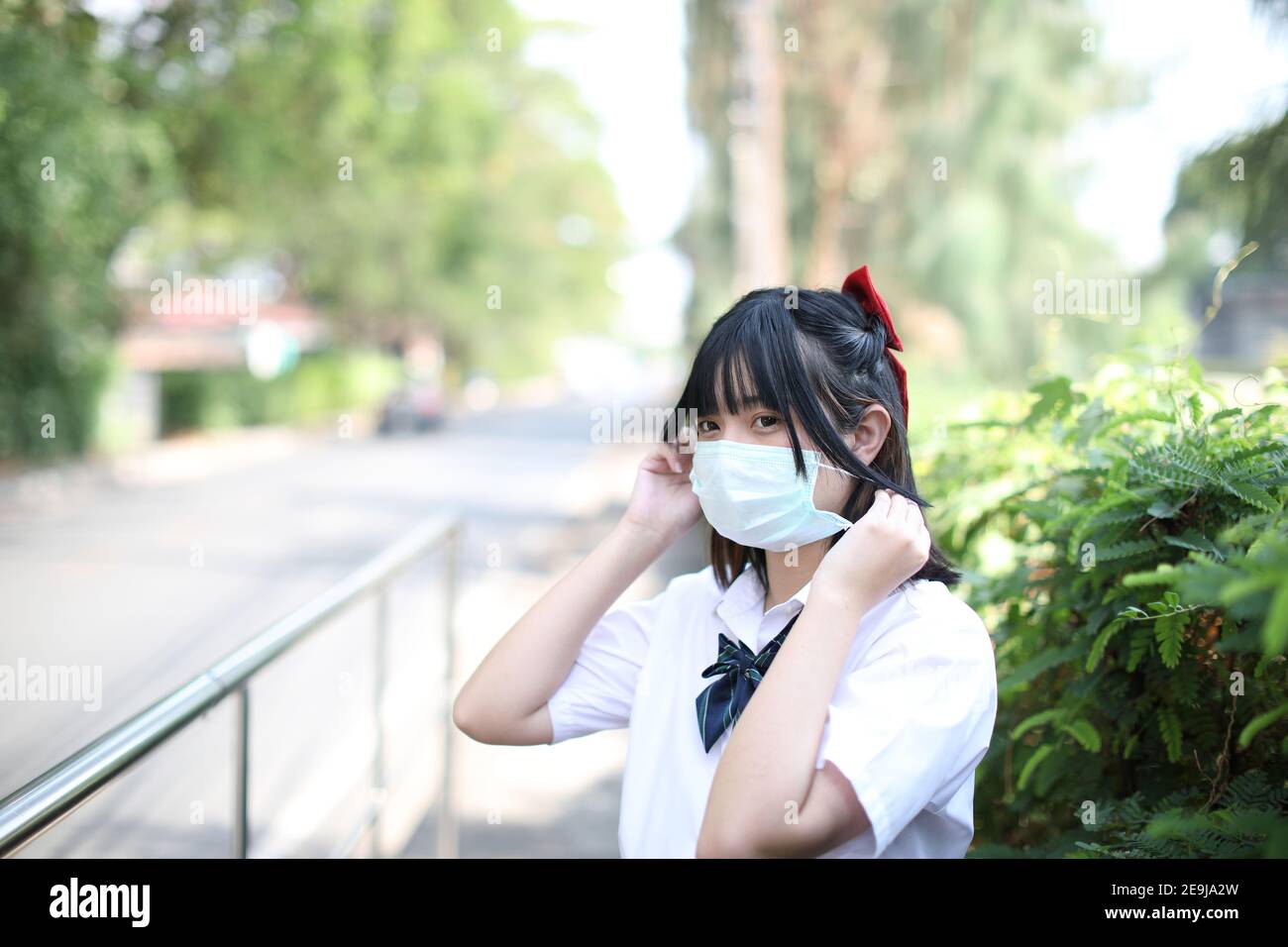 Asiatische Schule Mädchen mit Maske in Gehweg Stadt Stockfoto