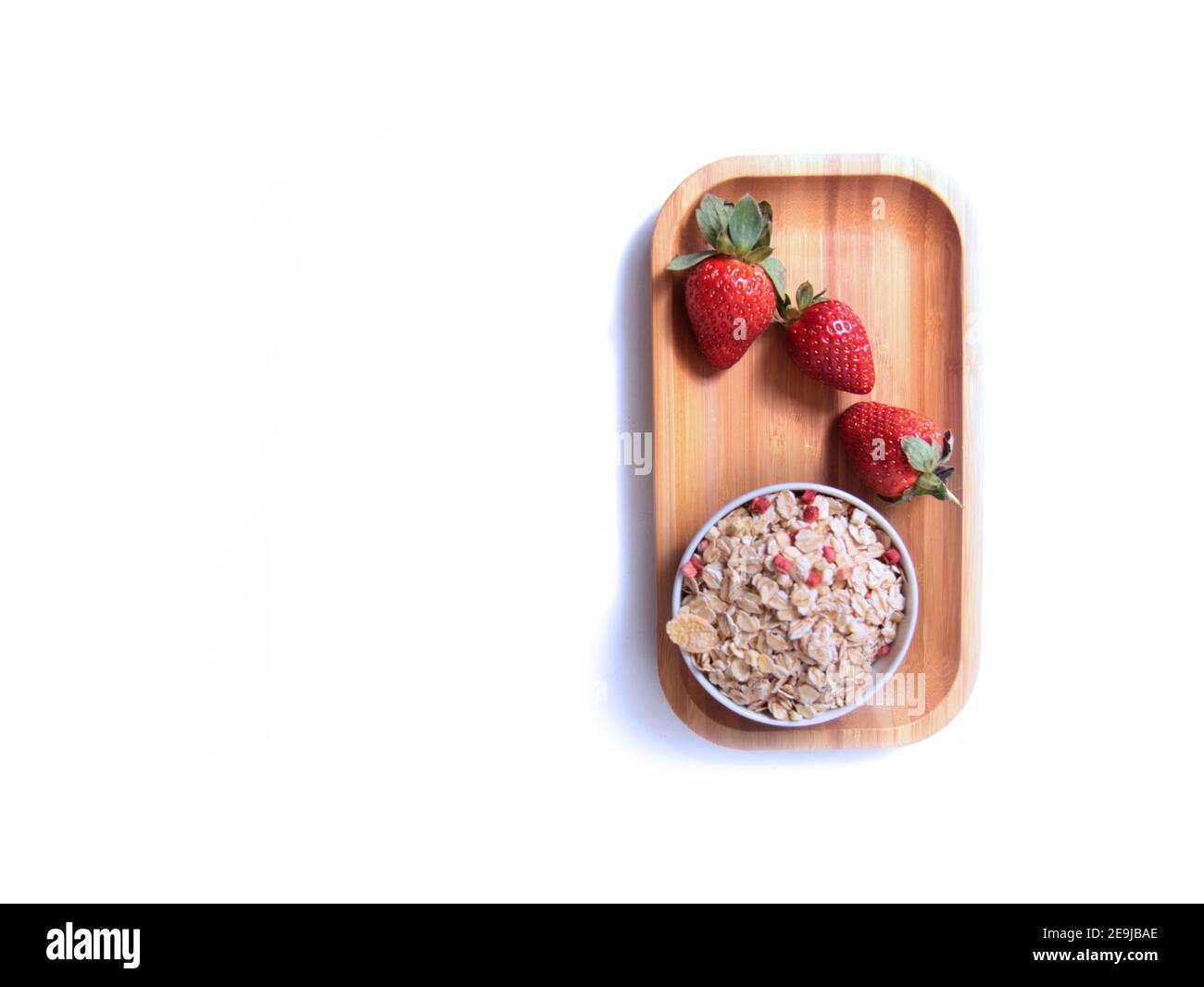 Erdbeeren und eine Schüssel Müsli auf Holzplatte isoliert vor weißem Hintergrund flach legen. Gesunde Ernährung Konzept. Das Bild enthält den Kopierbereich Stockfoto