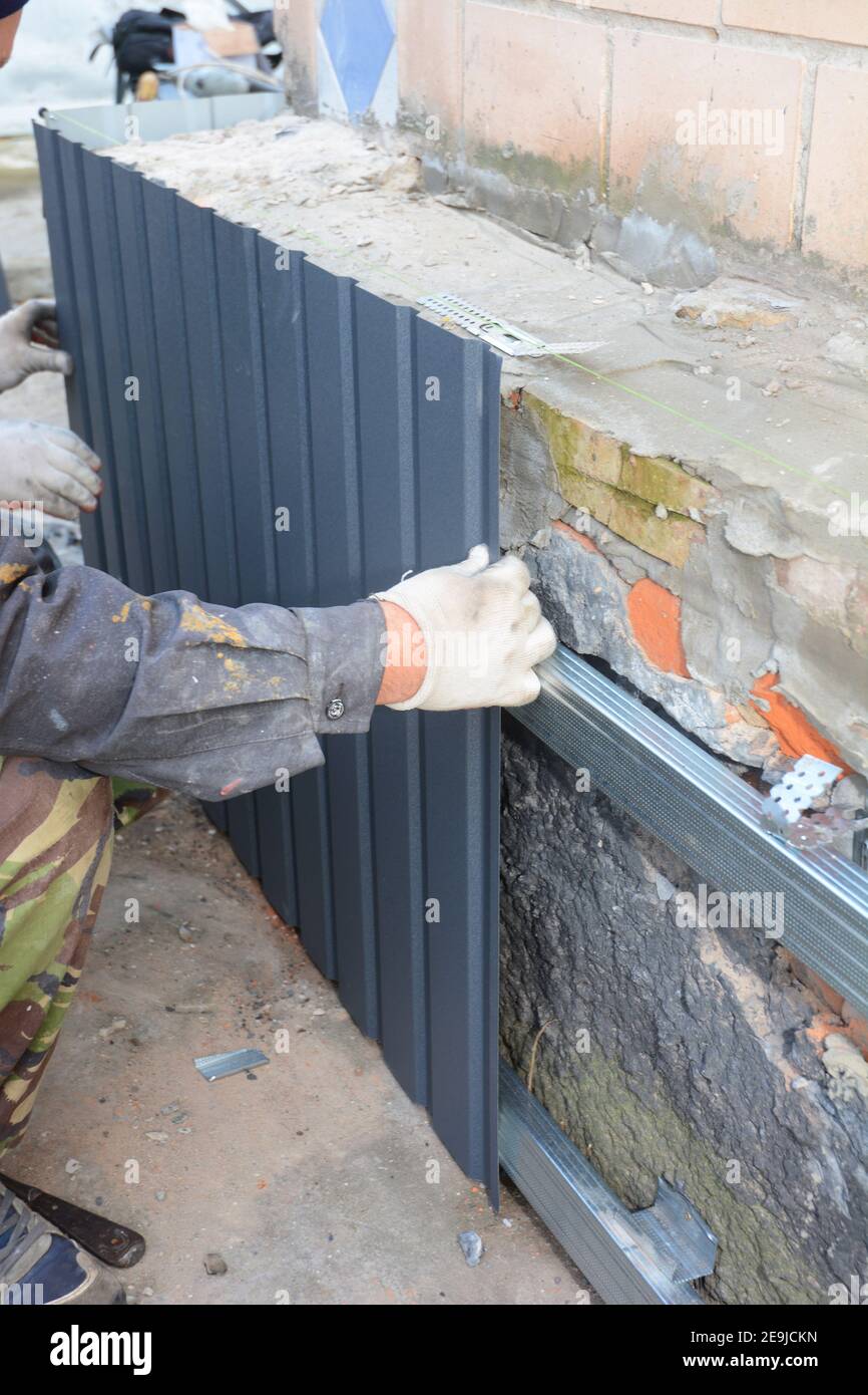 Altes Haus Fundament Wand reparieren und renovieren mit der Installation von Metallblechen für Abdichtung und vor Regen schützen. Fundamentreparatur. Stockfoto