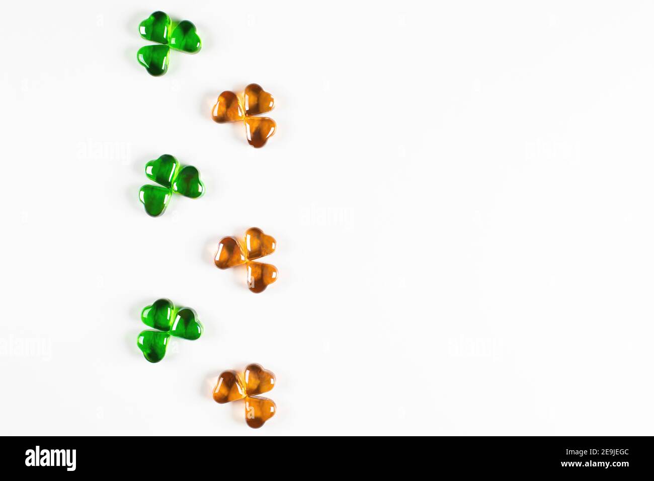 Shamrock Symbole aus grünem und orangefarbenem Glas Herzen auf Weißer Hintergrund Stockfoto