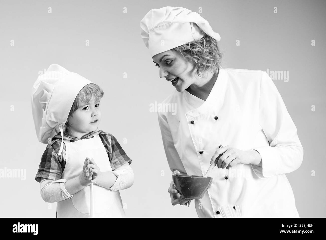 Mutter lehrt Sohn zu kochen. Mama und Kind mit viel beschäftigten Gesicht Kochen Essen zusammen. Stockfoto