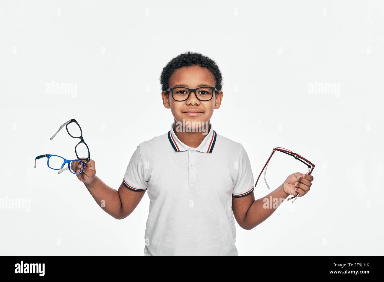 Afroamerikanischer Junge hält viele stilvolle Brillen in den Händen, für Sehkorrektur für Kinder. Isoliert auf Weiß Stockfoto