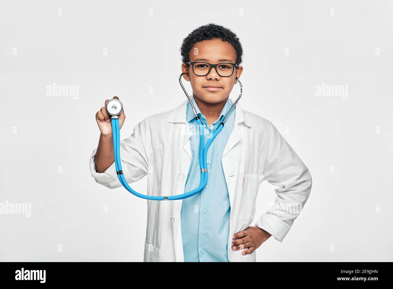 Porträt eines afroamerikanischen männlichen Kindes in einem Arztmantel mit Phonendoskop, auf hellgrauem Hintergrund stehend Stockfoto