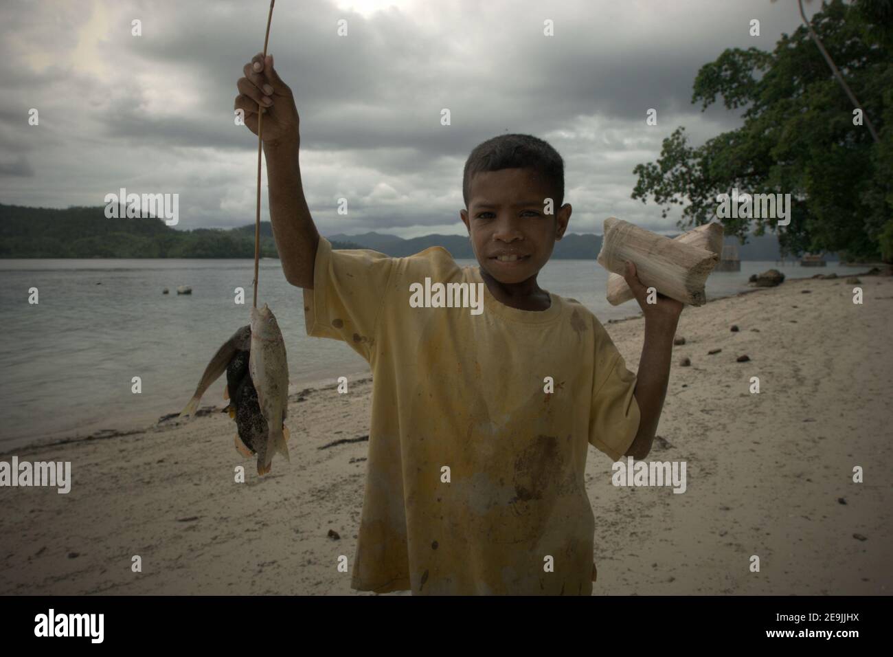 Paul Wawiyai zeigt seinen heutigen Fang am Strand von Friwen, einer kleinen Insel im Raja Ampat Archipel, wo der Lebensunterhalt von der Subsistenzfischerei abhängt. Stockfoto