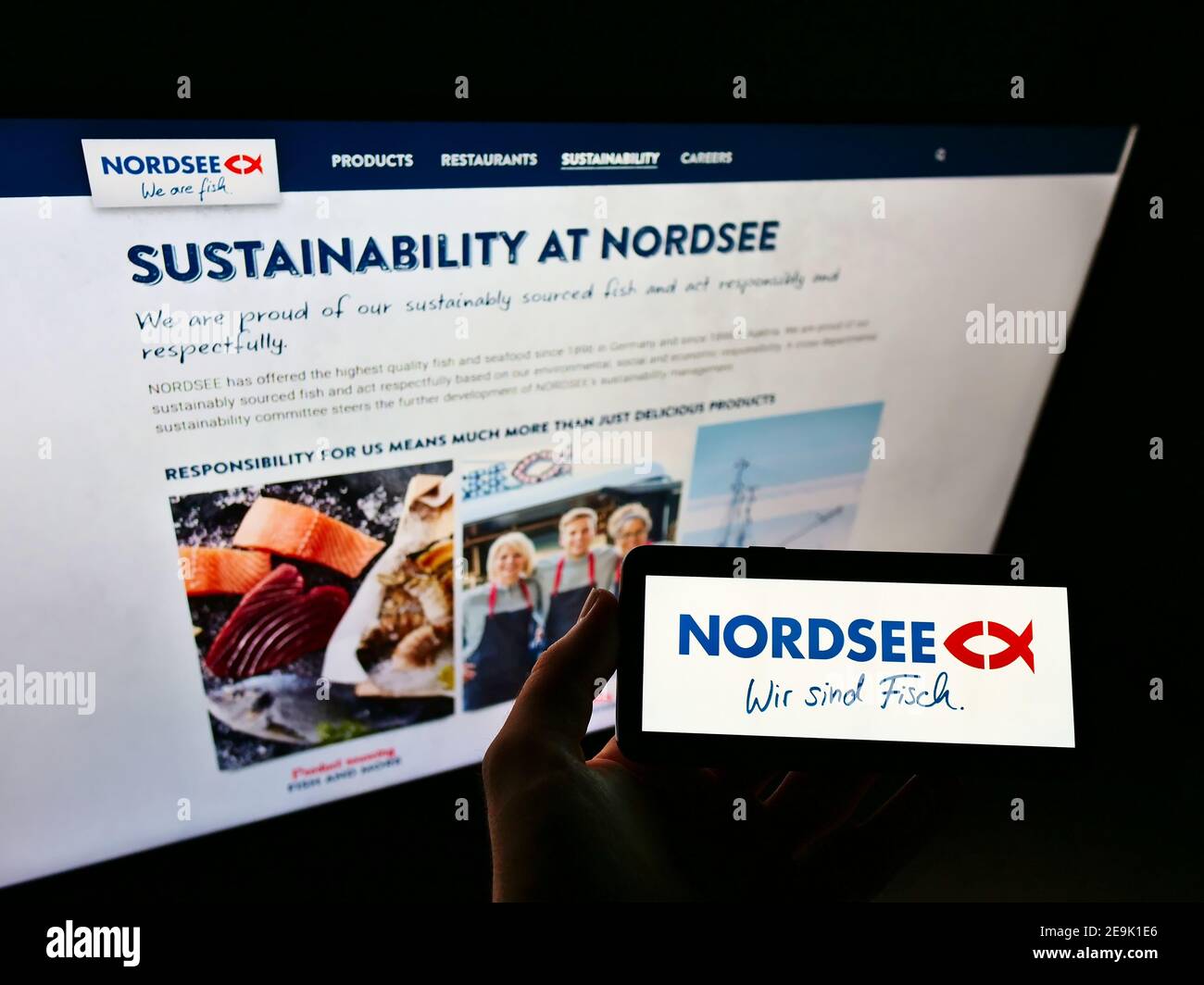 Person mit Mobiltelefon mit Logo der deutschen Fast-Food-Restaurantkette Nordsee GmbH auf dem Display vor der Webseite. Fokus auf Handy-Bildschirm. Stockfoto