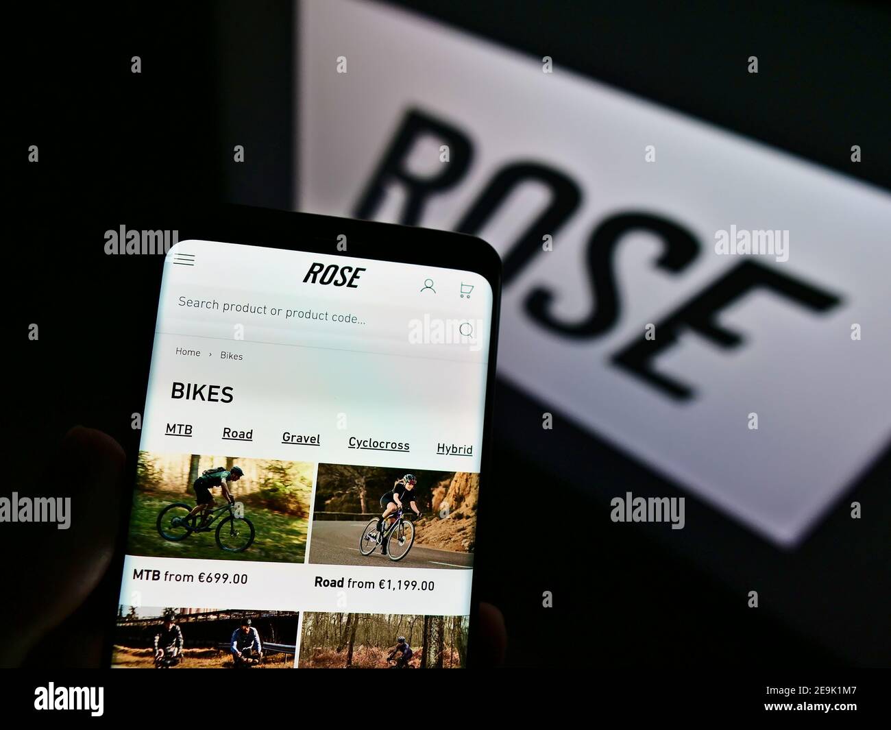 Person mit Smartphone mit Online-Shop des deutschen Fahrradherstellers Rose Bikes GmbH auf dem Display mit Logo. Konzentrieren Sie sich auf die Mitte des Telefonbildschirms. Stockfoto