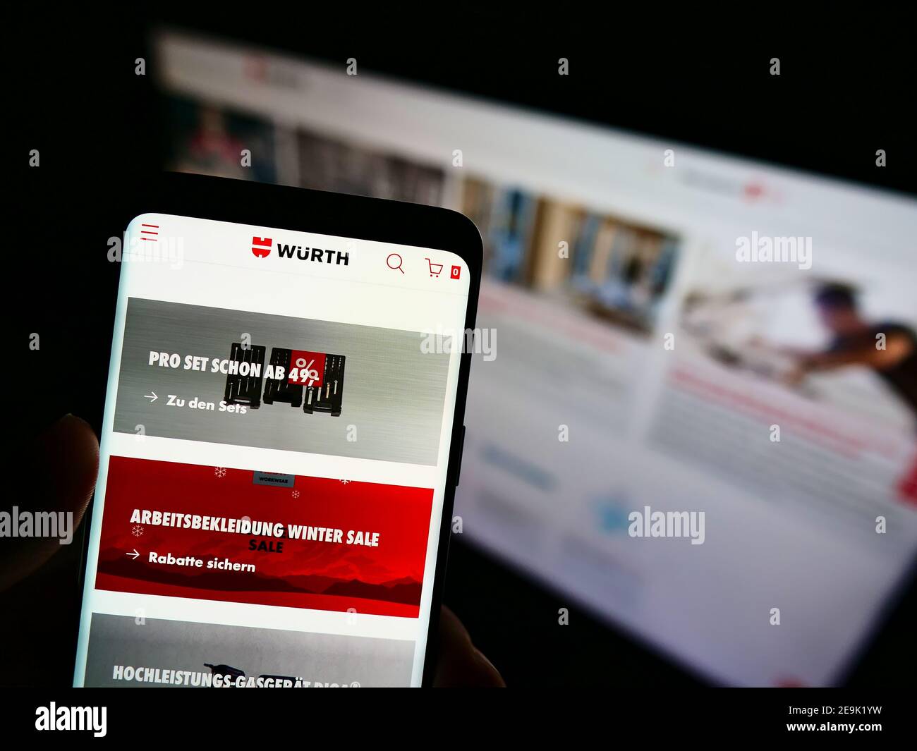 Person mit Smartphone mit Online-Shop des deutschen Großhandelsunternehmens Würth-Gruppe auf dem Display vor der Website. Fokus auf Telefonbildschirm. Stockfoto