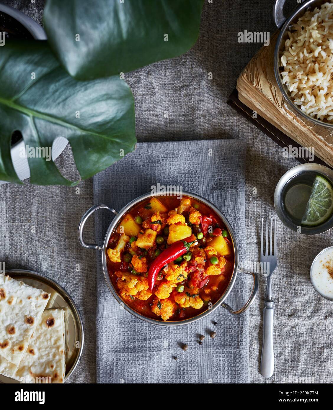 Aloo gobi traditionelle indische Küche aus Blumenkohl und Kartoffeln mit roten Chilischoten, serviert mit braunem Reis, Dahi, Zitronenwasser und Chapati auf der Ta Stockfoto