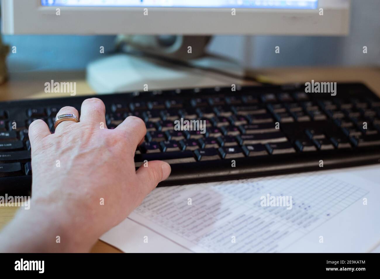 Mann, der mit der linken Hand auf einer Computertastatur tippt und von zu Hause aus arbeitet Stockfoto