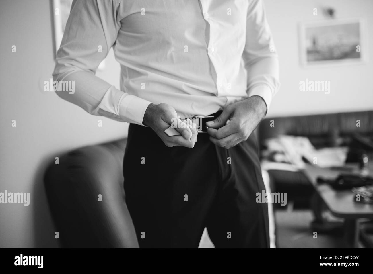 Graustufenaufnahme des Bräutigams in schwarzer Hose und weiß shirt mit Gürtelverschluss Stockfoto