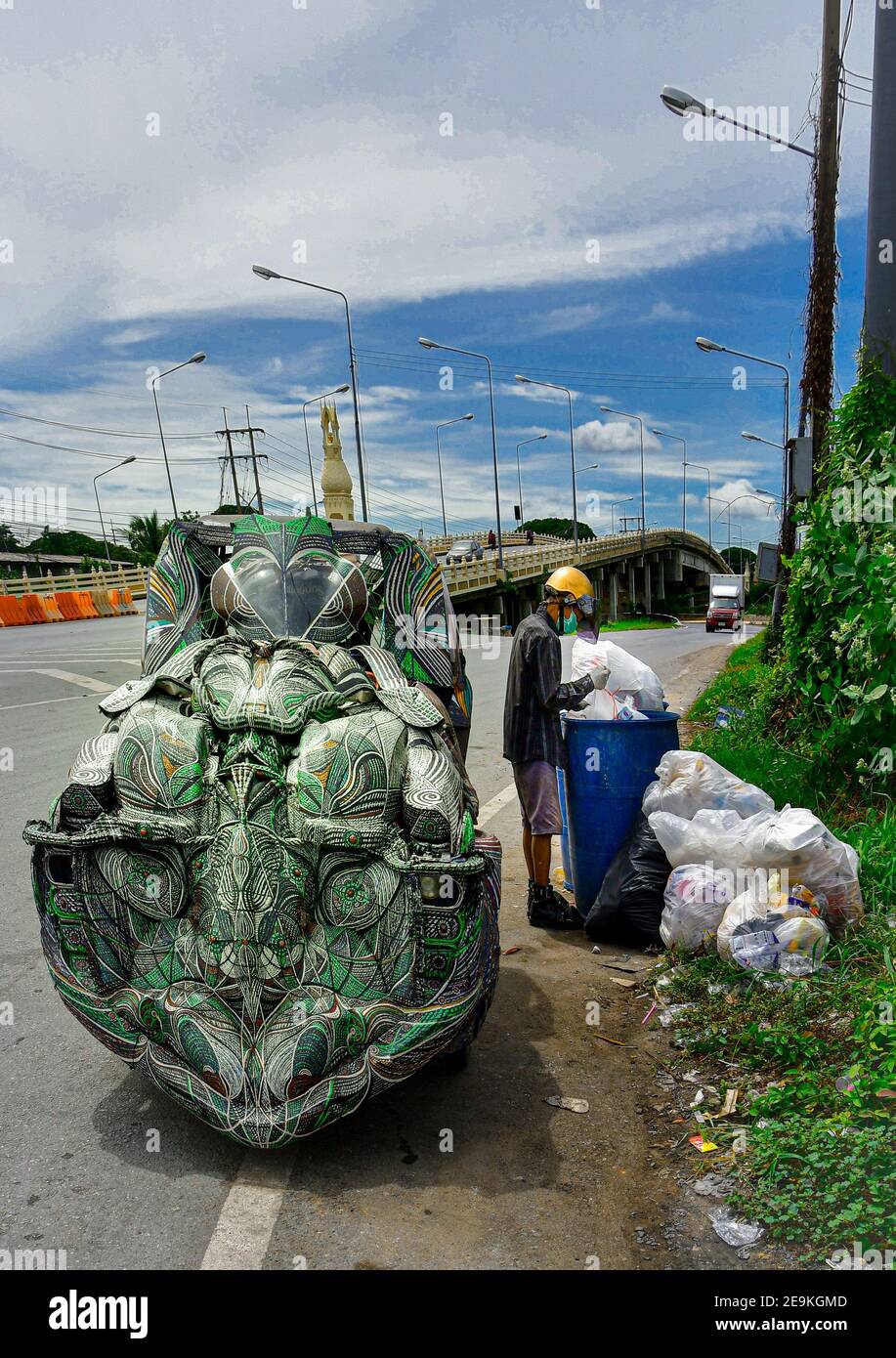 Ein alter asiatischer Mann stöbert durch einen Abfalleimer und sammelt in seinem maßgeschneiderten Fahrzeug recycelbare Gegenstände aus recyceltem Kunststoff. Stockfoto