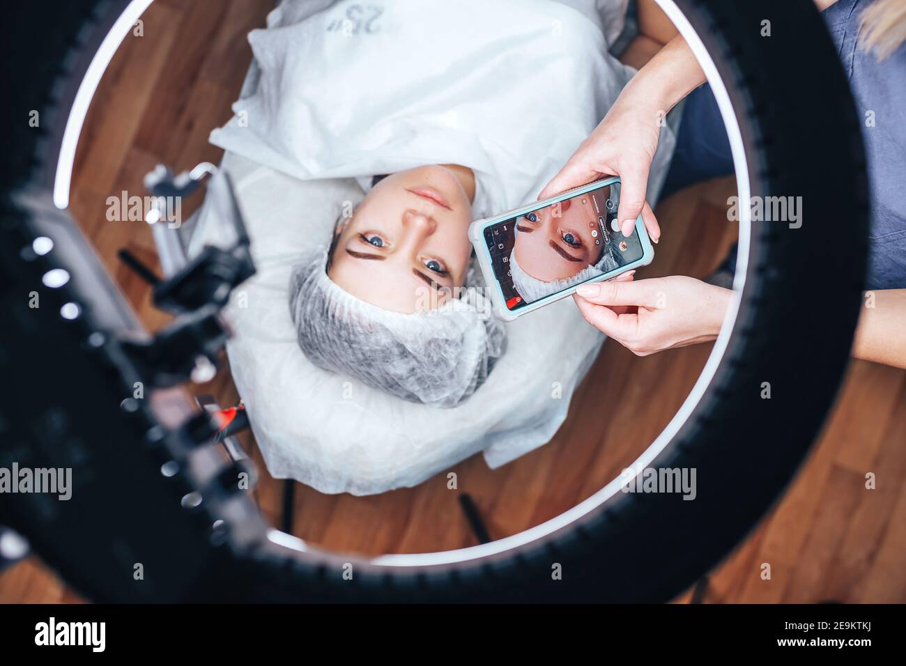 Die Kosmetikerin macht ein Foto von seiner Arbeit nach dem Permanentes Make-up Stockfoto