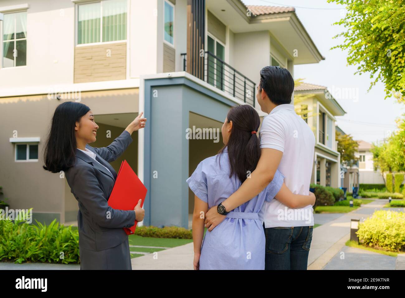Asian Woman Immobilienmakler, die dem jungen asiatischen Liebespaar, der es sucht und Interesse daran hat, es zu kaufen, ein Detail in ihrer Akte zeigt. Ein neues h kaufen Stockfoto