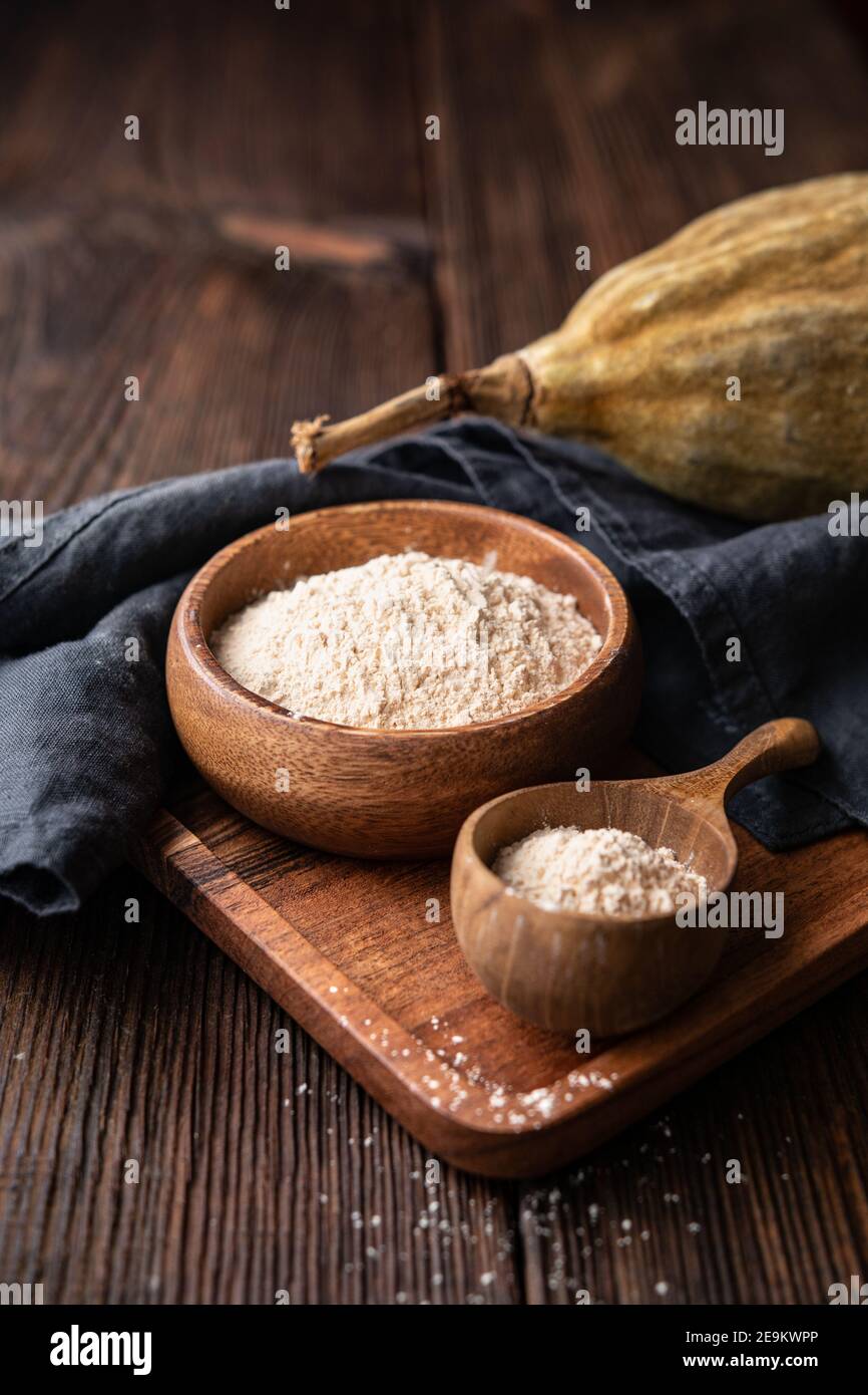 Bio Baobab Pulver in einer Holzschale auf rustikalem Hintergrund, gesunde Sportnahrung reich an Vitaminen und Mineralstoffen Stockfoto