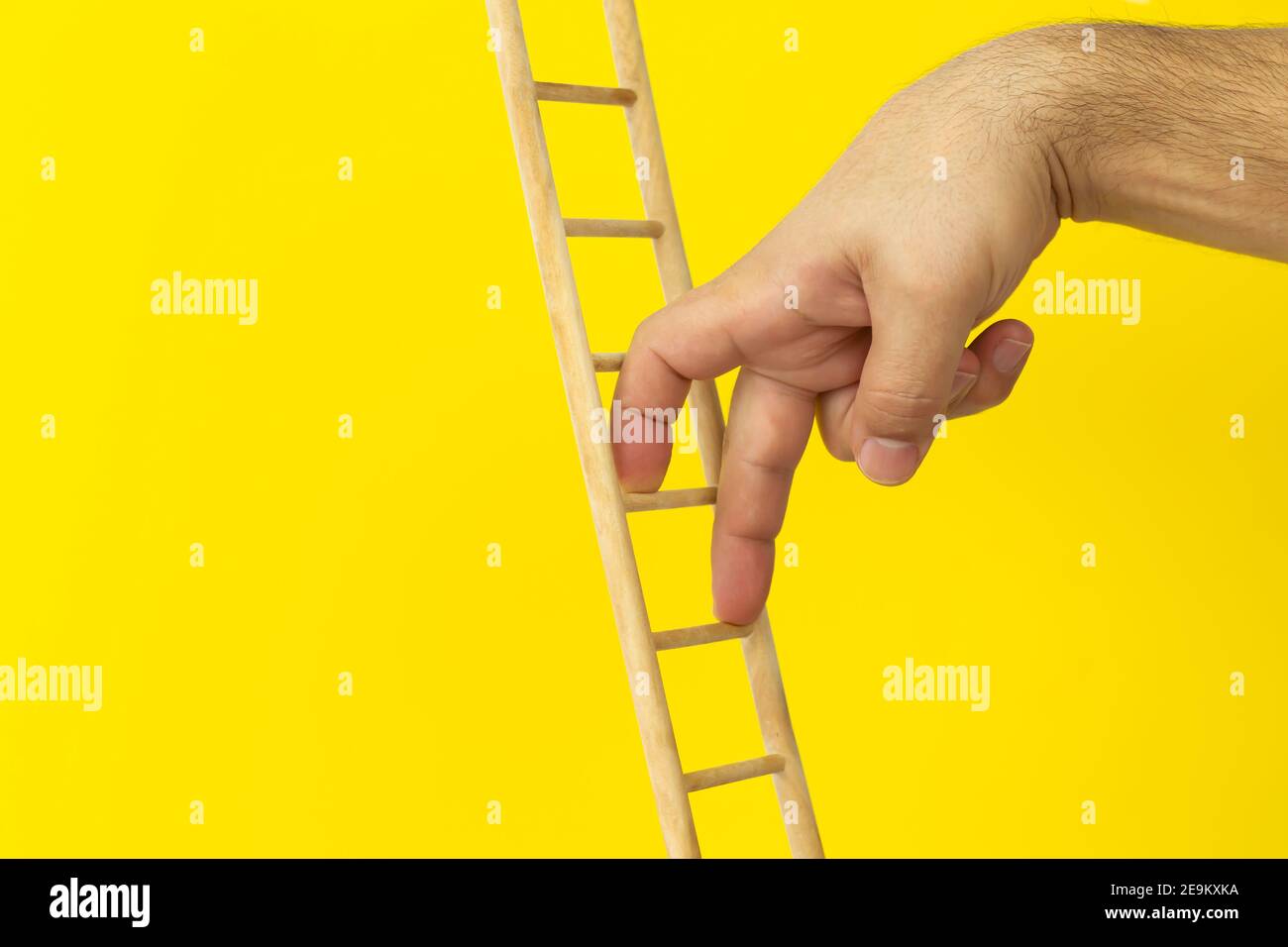 Persönliche Entwicklung, Karriereentwicklung und Führungskonzept. Männliche Finger klettern oben auf gelbem Hintergrund Stockfoto