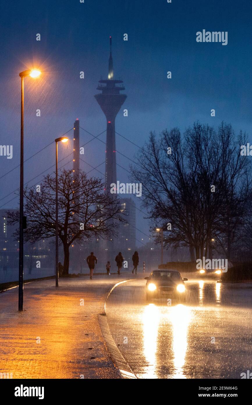 Starker Regen am Abend macht die Straßenverhältnisse in Düsseldorf am Rhein, im Hintergrund die Rheinkniebrucke und den Fernsehturm schwierig Stockfoto