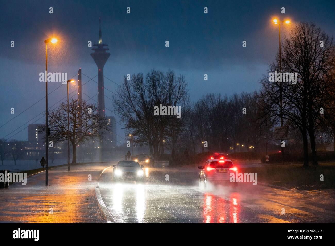 Starker Regen am Abend macht die Straßenverhältnisse in Düsseldorf am Rhein, im Hintergrund die Rheinkniebrucke und den Fernsehturm schwierig Stockfoto