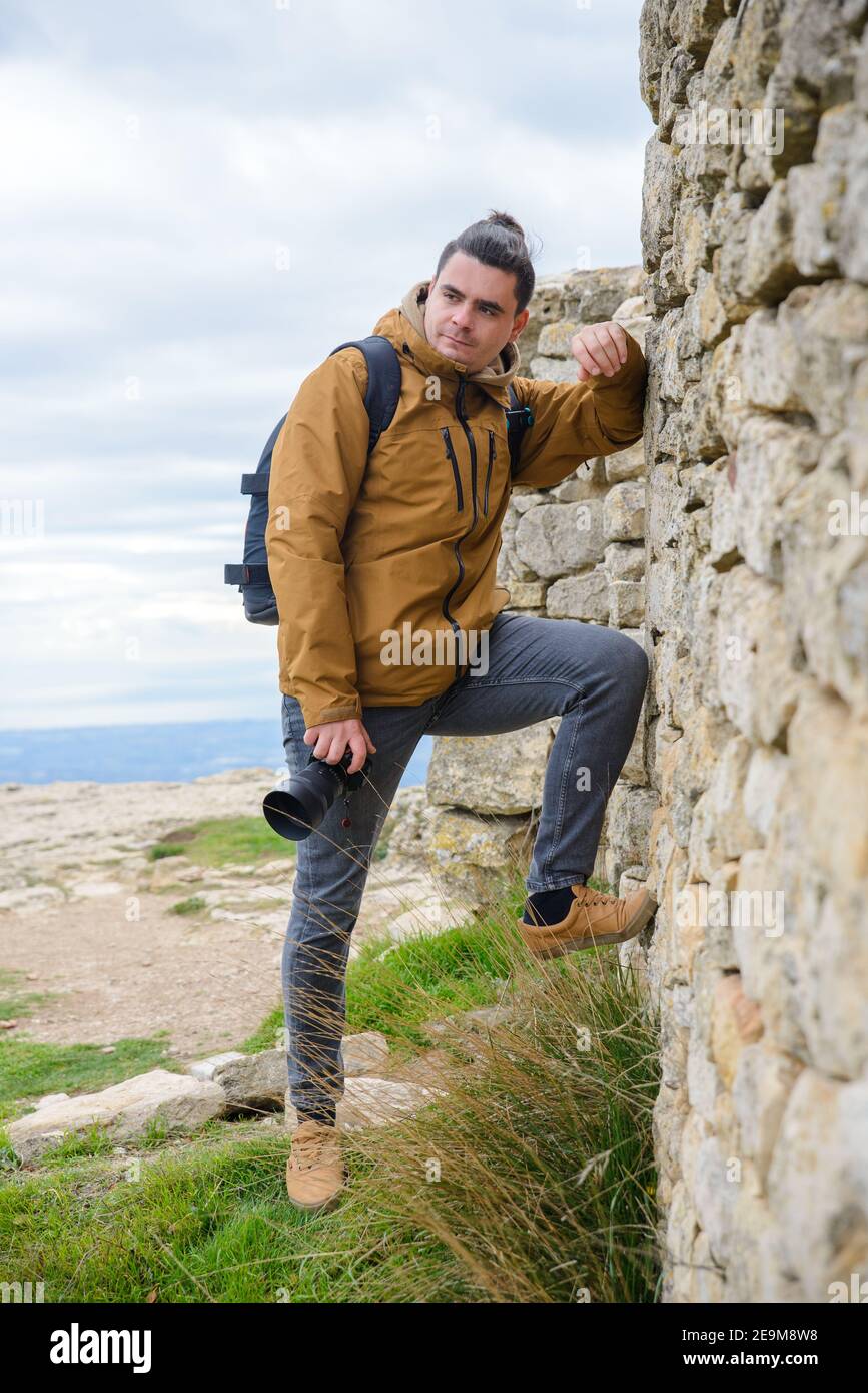 Außenfotograf, der sich an eine Wand lehnt Stockfoto