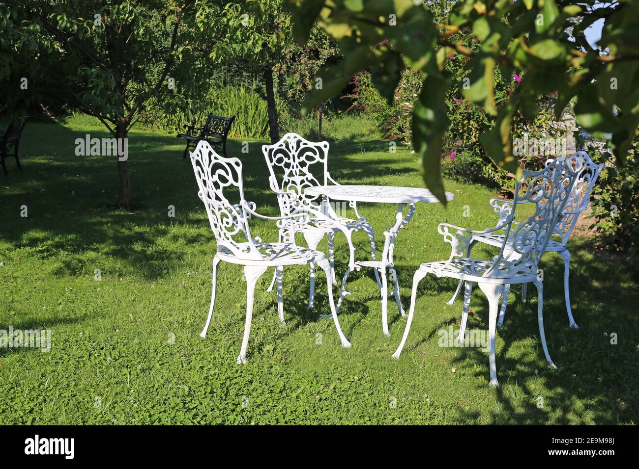 Gepflegter und gepflegter Obstgarten mit Gartenmöbeln in antik Design Stockfoto