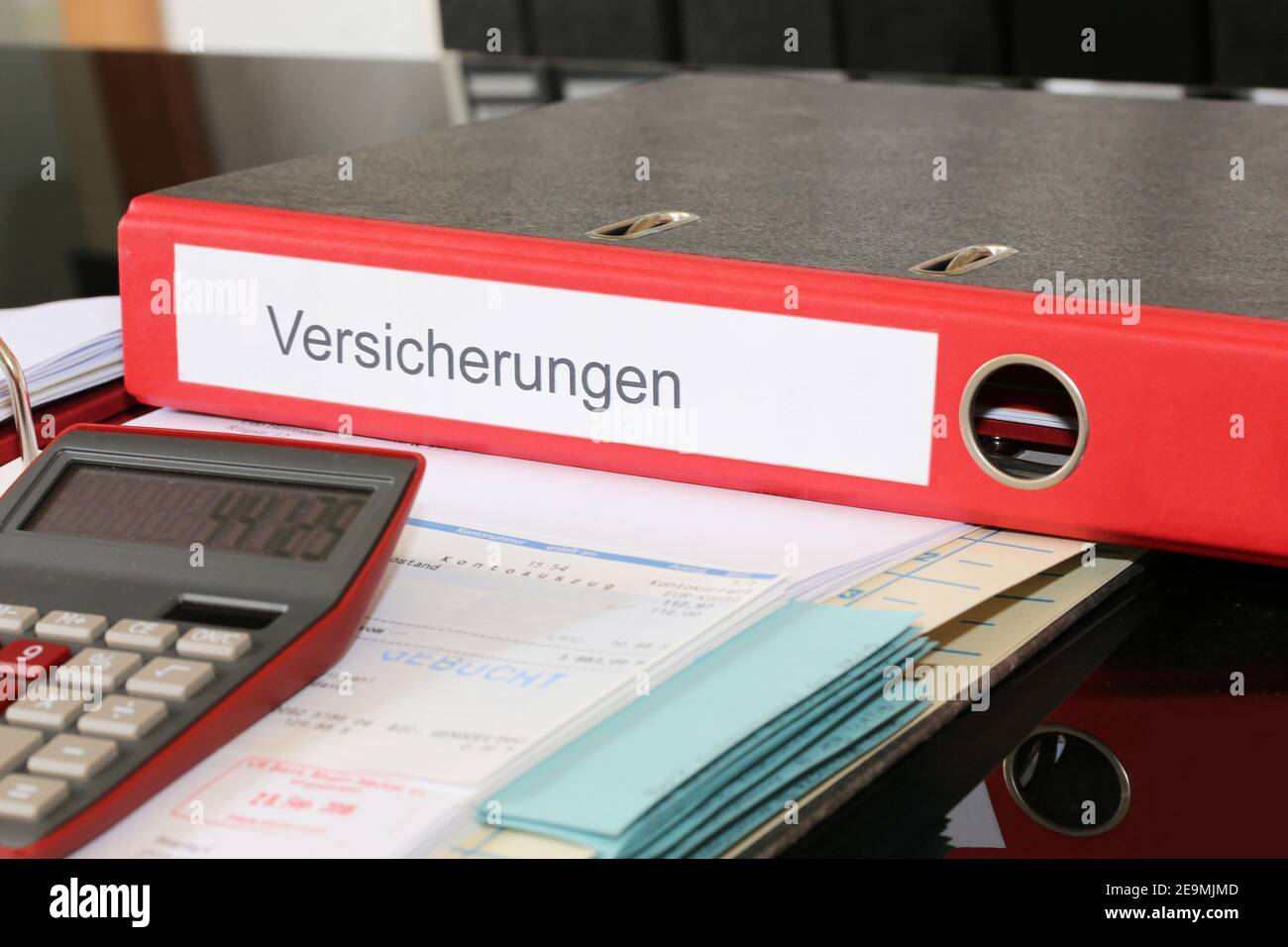 Symbolbild: Mappe mit Versicherungspolicen und Rechner auf einem Schreibtisch Stockfoto