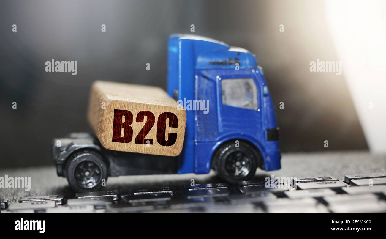 Holzblock mit B2C Abkürzung auf Spielzeugauto. Lieferung von Waren rund um den Globus im eCommerce. Business-to-Customer-Konzept. Logistische Netzwerk distributi Stockfoto