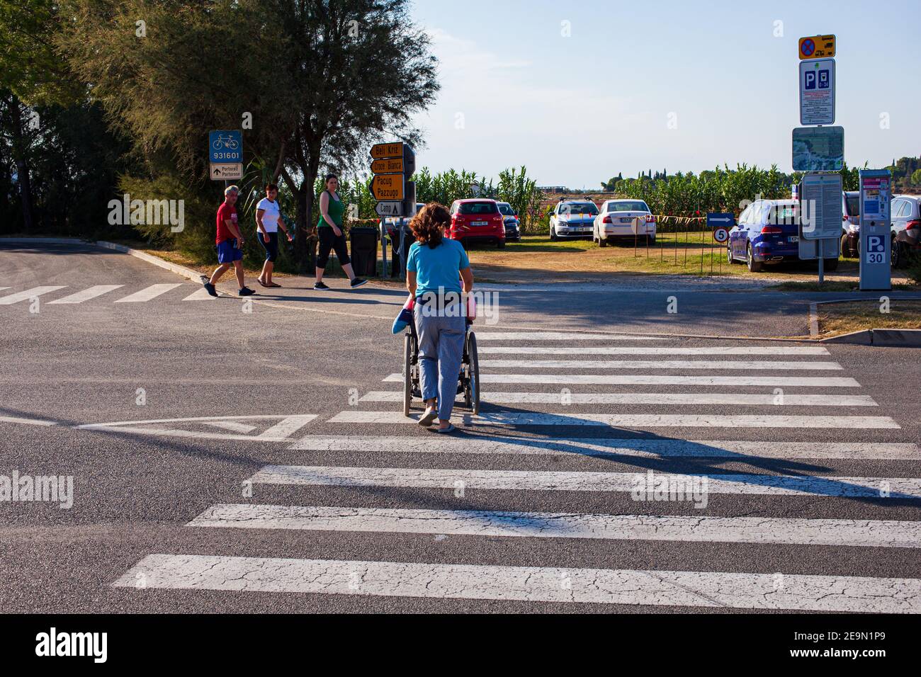Strunian, Slowenien - September, 19: Assistentin, die am 19. September 2020 behinderten Menschen im Rollstuhl beim Überqueren des Zebrakreuzes hilft Stockfoto