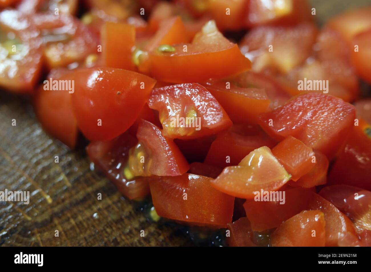 Zubereitung von Speisen zum Kochen: Gehackte rote Tomatenstücke in einer Nahaufnahme. Gesundes Gemüse für einen Salat oder ein Omelett verwendet werden. Hausmannskost. Stockfoto