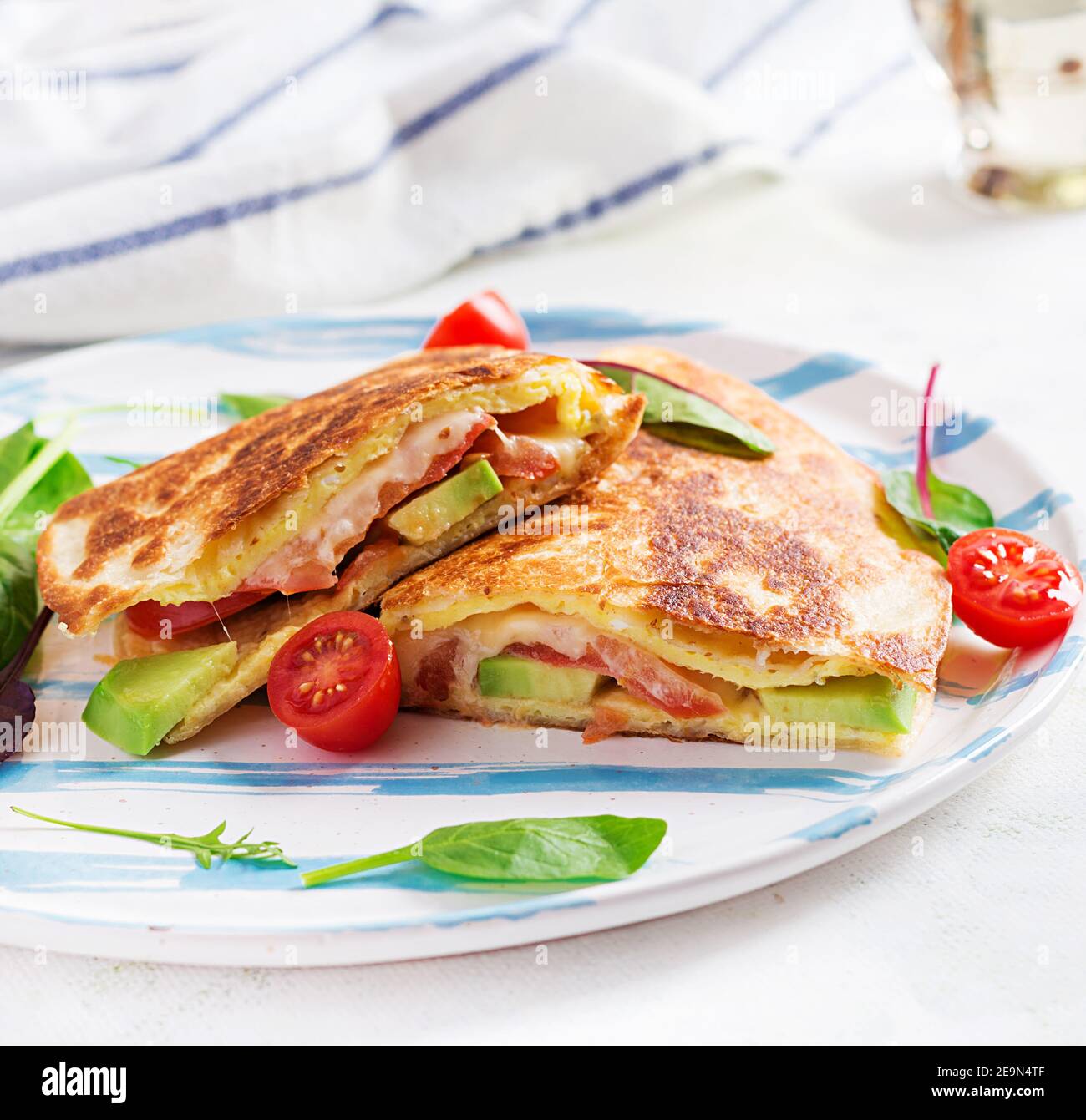 Leckeres Frühstück mit Quesadilla und Eiern. Mexikanische Küche. Trendgerichte mit Omelette, Käse, Tomaten, Avocado. Einfaches und leichtes Mittagessen. Stockfoto