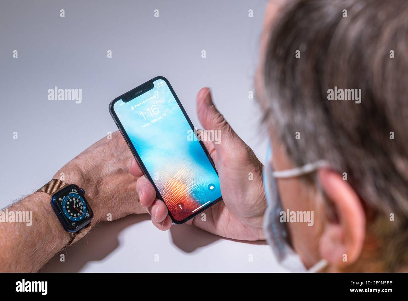 Morgantown, WV - 5. Februar 2021: Apple iphone und Uhr verwenden Gesichtserkennung, um das Telefon zu öffnen, auch wenn Sie eine Gesichtsmaske tragen Stockfoto