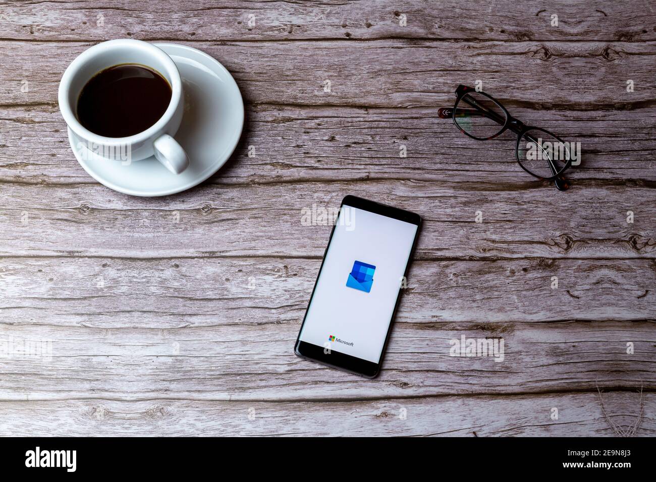 Ein Handy oder Handy auf einem Holz gelegt Tisch oder Schreibtisch mit geöffneter Microsoft Outlook-App Stockfoto